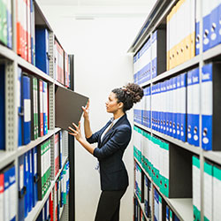 A woman retrieving a binder from the archives